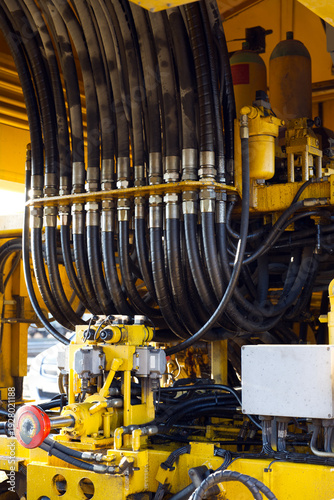 Foto A detailed close-up of heavy-duty hydraulic hoses and yellow machinery components