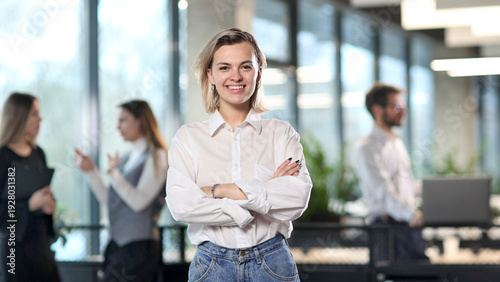 A woman in a white shirt and blue jeans stands in front of a group of people