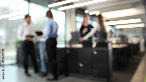 A group of people are standing in a room, some of them are holding laptops