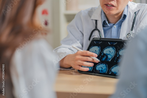 Konstfotografi Doctor explaining brain skull MRI scan on tablet to patient during consultation at clinic highlighting neurology diagnosis medical discussion healthcare technology imaging concept professional care