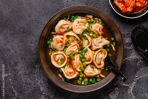 Dumplings served in a bowl with broth and green onions.