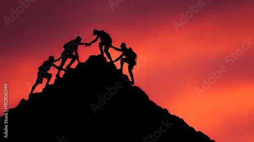 Silhouetted individuals assisting each other reaching mountain peak at sunset