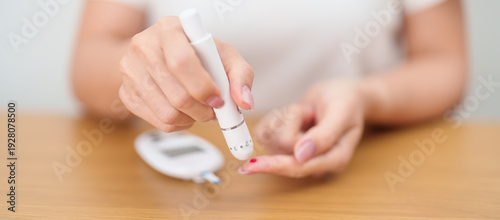 Fotografía Hand using lancet pen on finger with Blood drop glucose testing or Diabetes checking by digital blood glucose meter