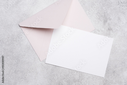 Bilde på lerret Blank invitation or greeting card mockup with a soft pink envelope placed on a t