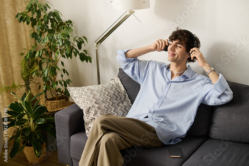 Fotografija Curly-haired young man enjoying music in his stylish modern apartment setting