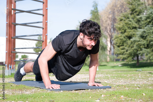 Fotografie Determined Young Man Performing Push-Ups in Outdoor Park