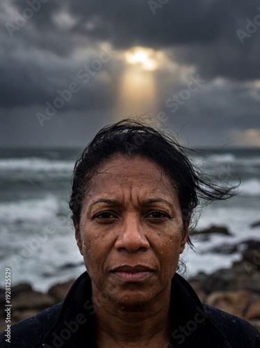 Resilient Black Woman Standing Against Stormy Ocean with Dramatic Sunlight Breaking Through Clouds