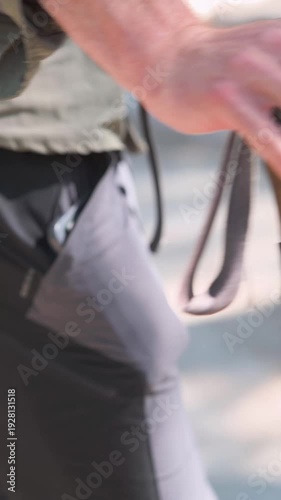 Close-up of a hiker's hand gripping the handle of a trekking pole during an outdoor adventure, highlighting hiking gear, endurance, and stability on the trail.