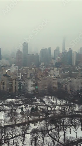 Sweep over Central Park winter snow paths with Manhattan skyline in dense fog