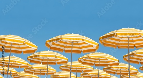 Yellow and White Striped Beach Umbrellas Against a Clear Blue Sky.