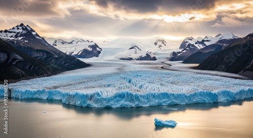 A majestic glacier in Patagonia, with snow-capped mountains in the background and a calm body of water in the foreground. 