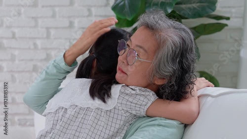 Embracing Generations: A tender embrace shared between a grandmother and her granddaughter. Captured in a warm indoor setting, this photo encapsulates the essence of family bonds.