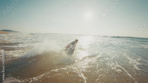 Hippie surfer. Young man in colorful stylish shirt walks on the beach and enters the ocean. Brazilian hippie surfer