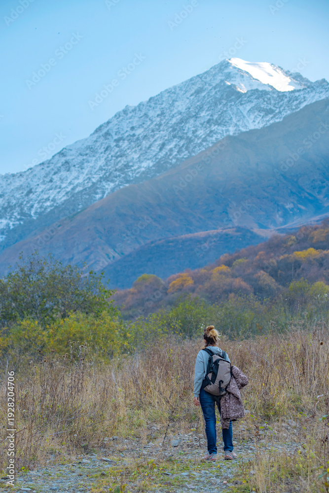 Obraz premium Female Backpacker Hiking Towards Snow Capped Mountain Peak with Copy Space