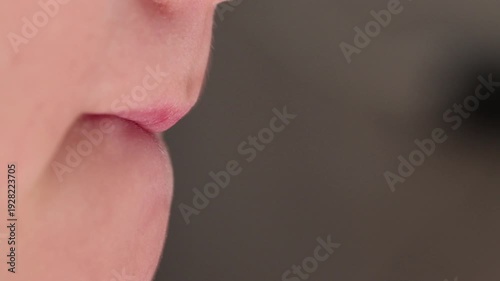 Extreme macro close-up of a young boy's lips pursing and compressing in a side profile. 
