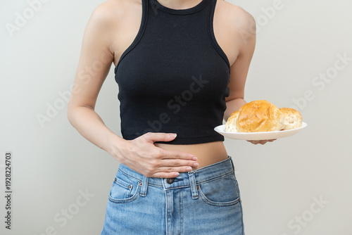 Gluten allergy, asian young woman hand holding, refusing to eat white loaf slice on plate in breakfast food meal at home, girl having a stomach ache. Gluten intolerant and Gluten free diet concept.