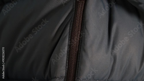 Extreme macro close-up of a person zipping up a warm winter jacket.