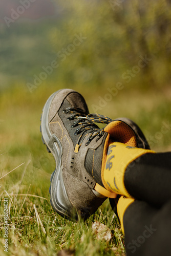 Closeup of hiking boot resting on green grass in sunny meadow. Outdoor adventure, travel lifestyle and exploration concept. Comfortable trekking footwear for journey, nature recreation