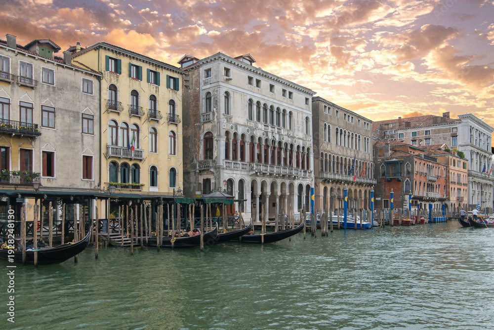 Fototapeta premium Black gondolas near historic Venice palazzos at golden sunset