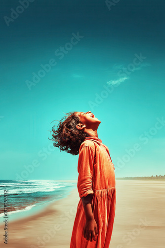 A joyful child with windblown hair laughs openly while facing the ocean on a sunny beach