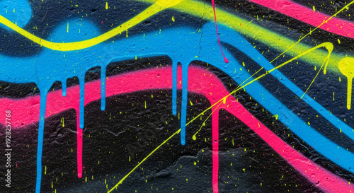 Spray paint graffiti texture with layered drips and splatters in electric blue, hot pink, and neon yellow against dark background.