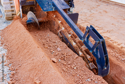 Heavy machinery digs trench in ground for construction work in residential area
