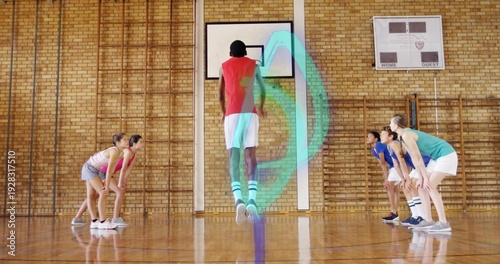 Obraz na plátně Jumping teen hooper shooting toward backboard at school gym wearing red jersey w