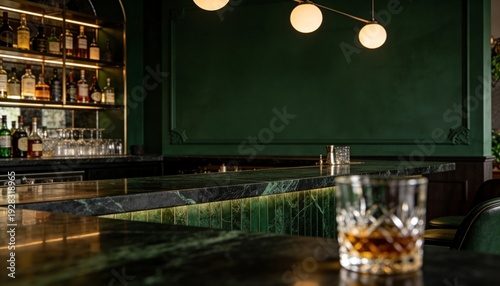 Elegant bar interior with whiskey glass, illuminated shelves, and plush green seating, upscale ambiance.