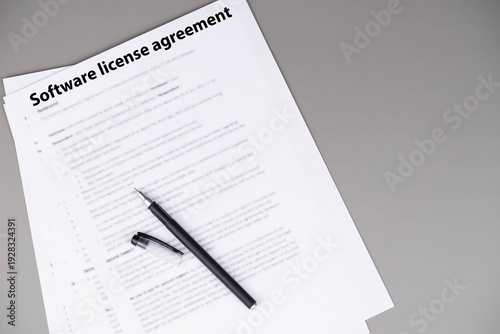 Software license agreement document on office desk, legal contract granting rights to use software under specific terms, symbol of digital compliance, intellectual property, and business technology.