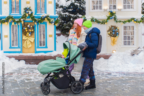 Photos Mother with teenage son and infant in baby carriage exploring festive Christmas decorations in Moscow city center during winter holidays