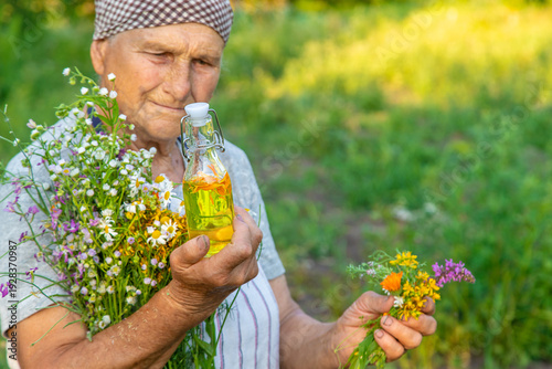 Fotografie Old woman makes herbal tincture. Selective focus.