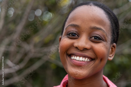 Photography Adult African American woman smiling while facing camera in park, wearing pink c