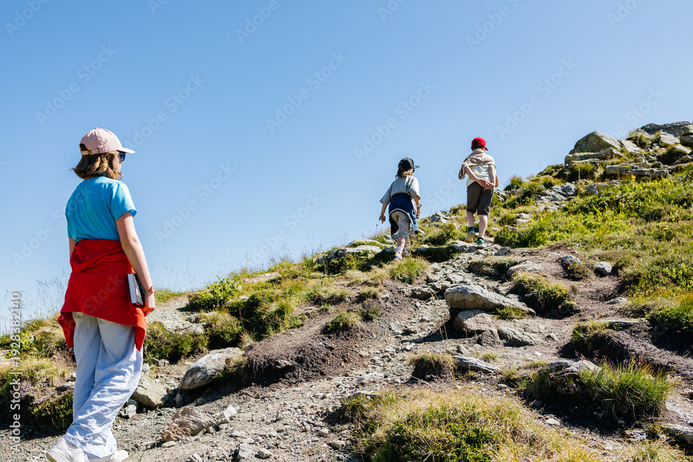 Obraz premium Children hiking up a mountain trail on a sunny day
