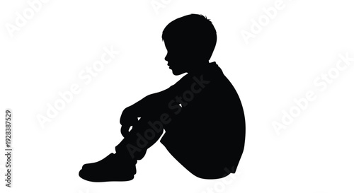 Young boy sitting and looking down in stark contrast a silhouette