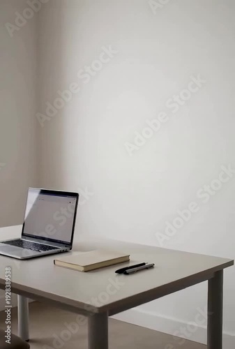 Minimalist workspace with laptop and notebook on white desk