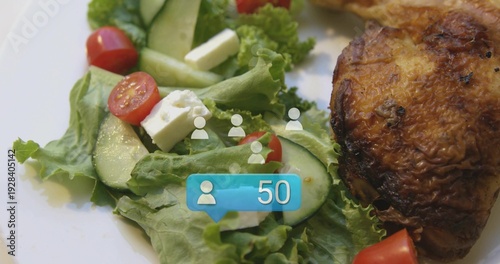 Showing white plate with lettuce, cucumber, tomatoes, feta cubes and roast thigh on table, badge 50