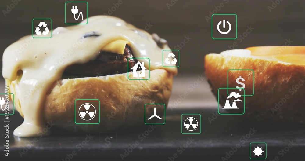 Fototapeta premium Showing cheeseburger with melted cheese oozing toasted bun and patty on dark table with green icons