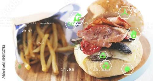 Obraz Showing bacon-topped burger sitting right on wood board, with fry cone, blue paper, green UI