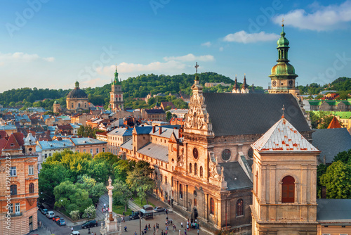 Aerial drone view of Lviv, Ukraine featuring historic churches, cathedral towers, and colorful rooftops in the old town city center. European cityscape with green trees and architectural landmarks see