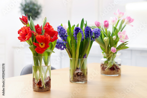 Beautiful spring flowers in vases on wooden table indoors, closeup