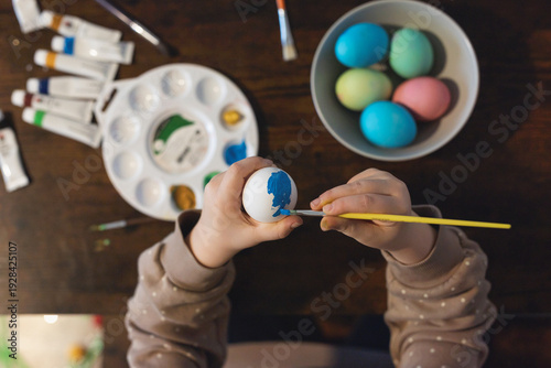 Girl painting easter egg, top view