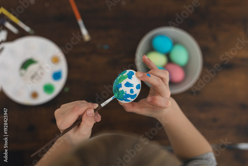 Boy painting easter egg, top view