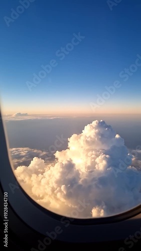 Wallpaper Mural A serene airplane window view of a majestic cumulus cloud at sunrise or sunset above the vast expanse of blue sky and sea of clouds, ideal for travel and nature concepts Torontodigital.ca
