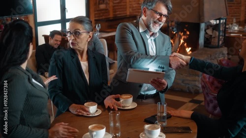 Handshake during business meeting in restaurant over coffee. Group of business people negotiating strategy and reaching agreement through collaboration