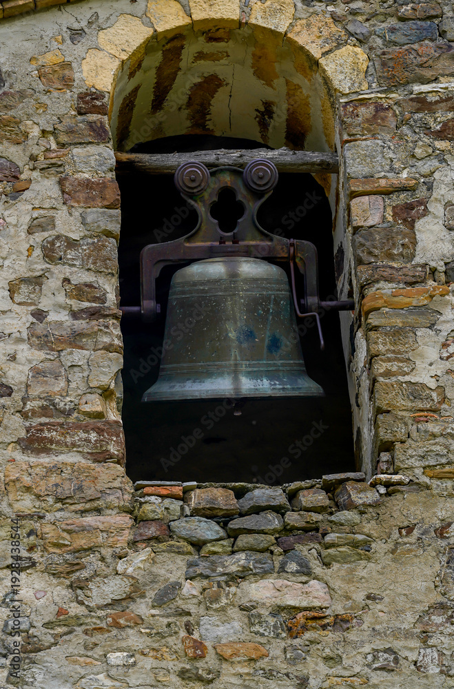 Obraz premium Close-up of ancient bronze bell in stone arch