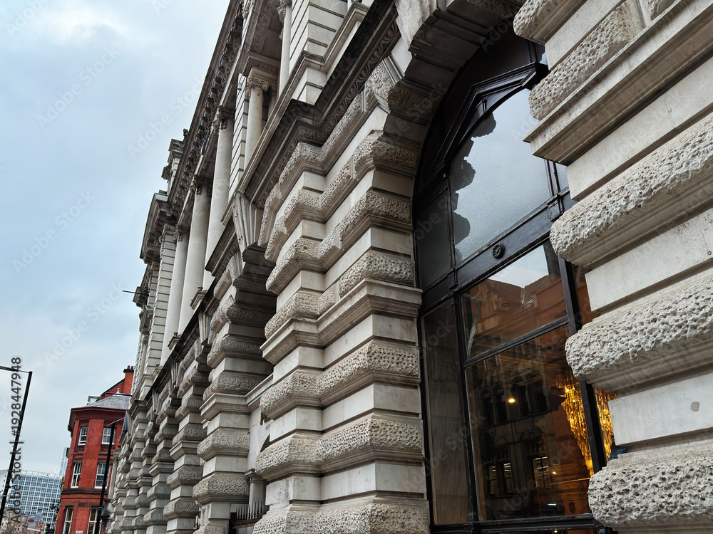 Fototapeta premium Historic stone building facade with arched window in Manchester UK street scene