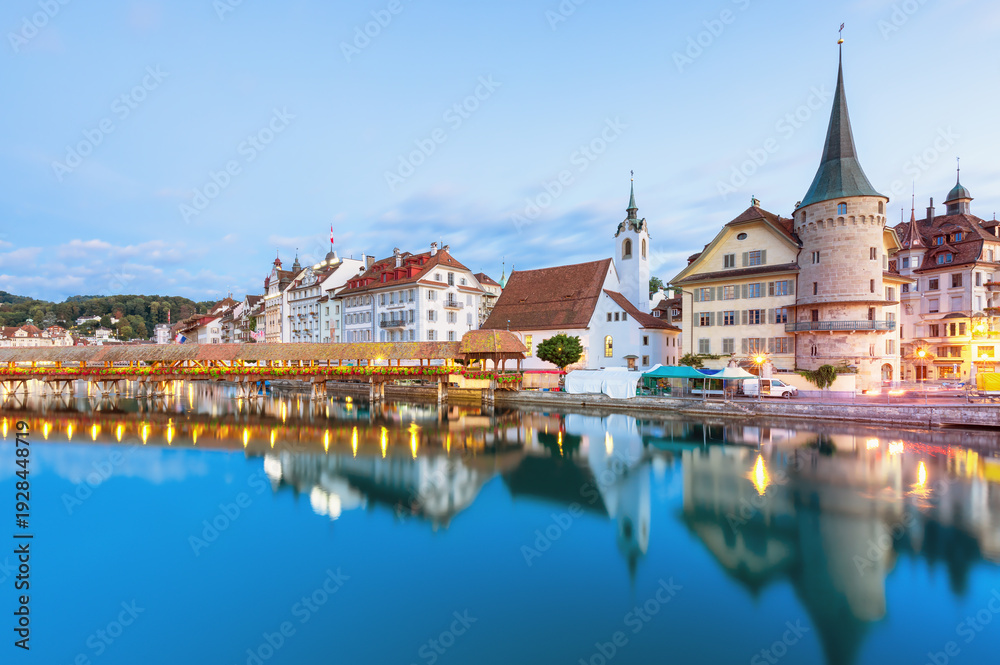 Obraz premium Beautiful view of Lucerne, Switzerland featuring the famous wooden Chapel Bridge with Water Tower over the Reuss River. Scenic cityscape with alpine mountains, clear water, and colorful historic archi