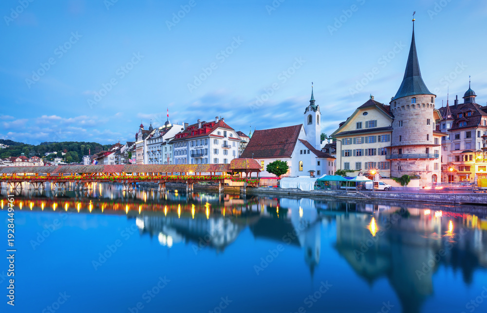 Obraz premium Beautiful view of Lucerne, Switzerland featuring the famous wooden Chapel Bridge with Water Tower over the Reuss River. Scenic cityscape with alpine mountains, clear water, and colorful historic archi