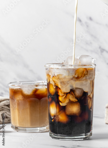 Slika na platnu Iced coffee with oat milk creamer swirl