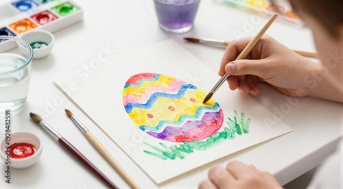 Child painting colorful easter egg with watercolor on tabletop